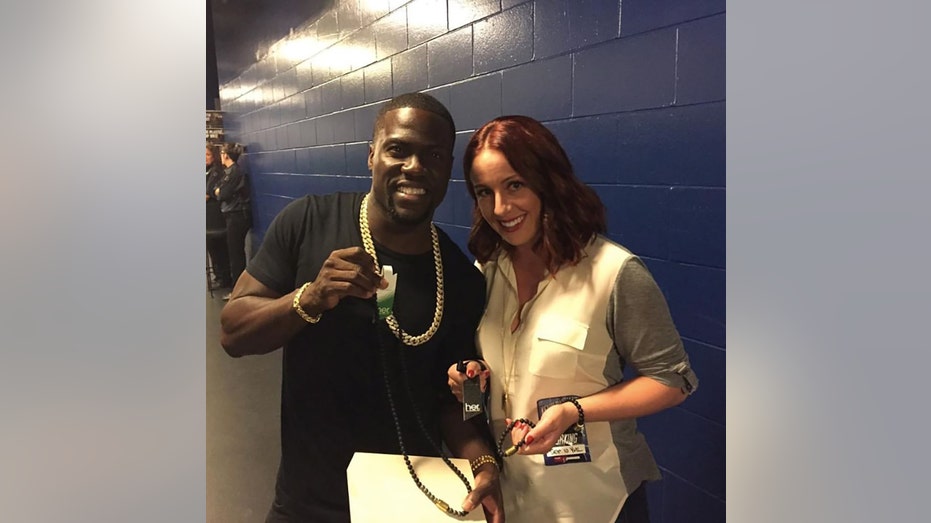 Kevin Hart wearing a black shirt smiling and pointing at the camera with Kelsi Sheren
