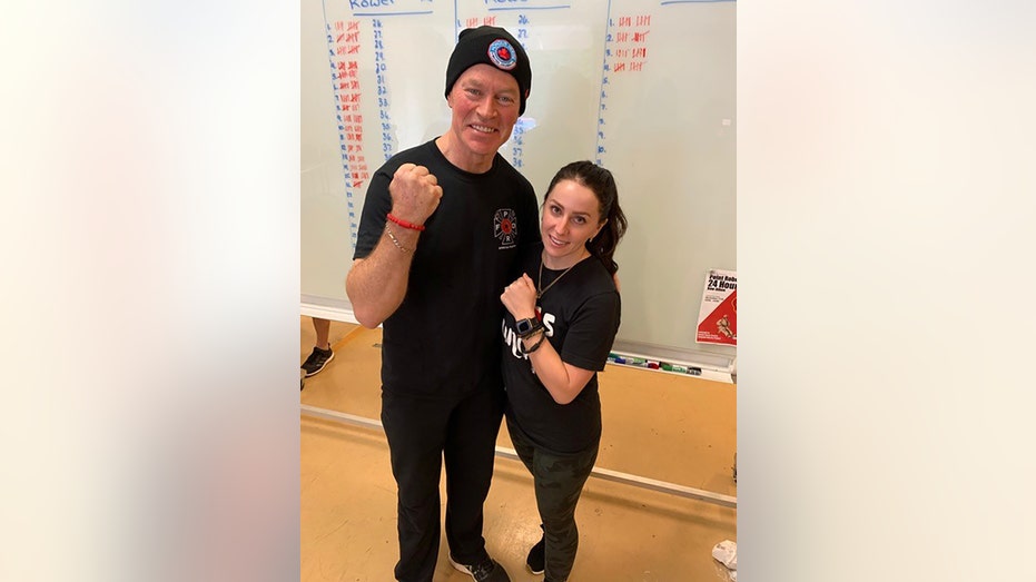 Kelsi Sheren and Neal McDonough holding up their fists as they wear matching black outfits