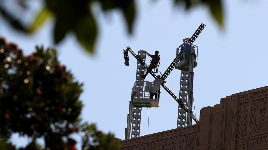 Workers prepare to take apart the X sign