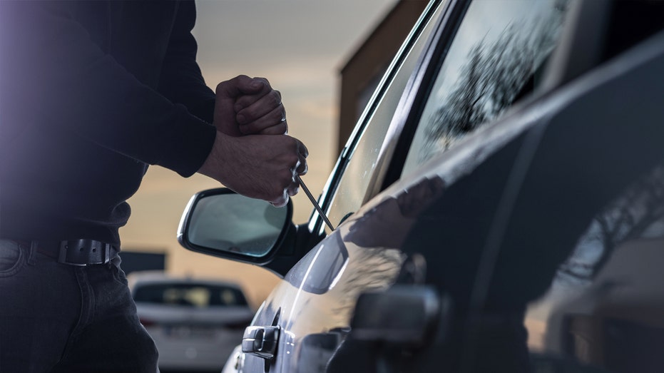 Person uses a tool to try to break into car.