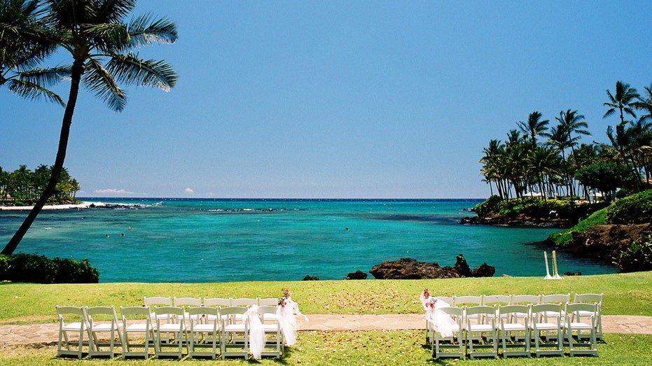 A wedding ceremony set up with chairs next to a view of a tropical lagoon in Maui.