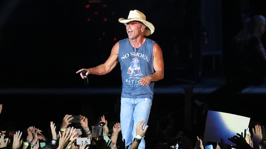 Kenny Chesney wears blue tank top and jeans in concert
