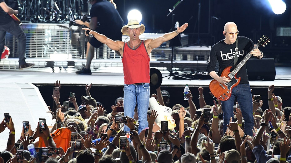 Kenny Chesney waves his hands in the air during concert