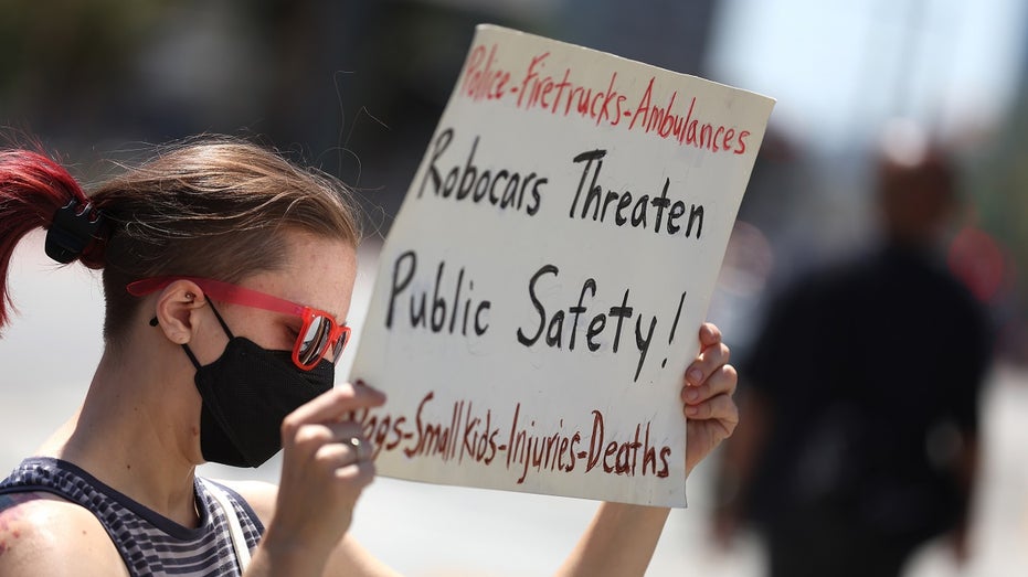 protestor holds sign against robotaxis