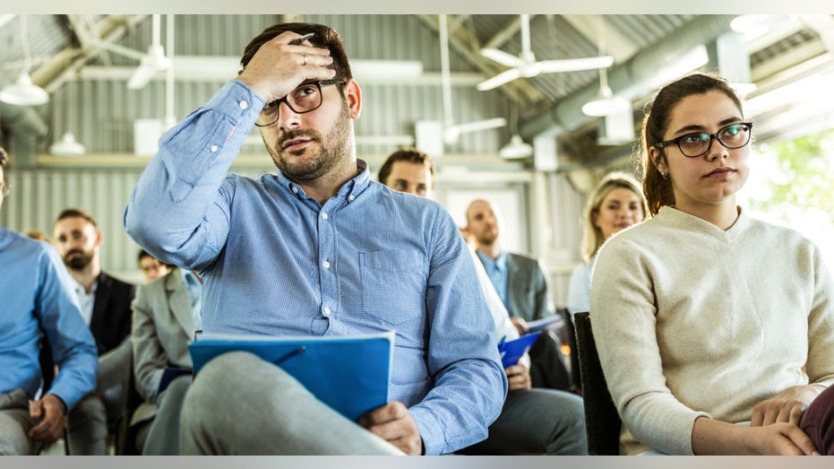 worker holding head during meeting