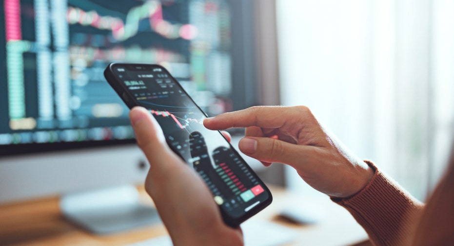 Close-up view a person's hands going over stocks on a smartphone.