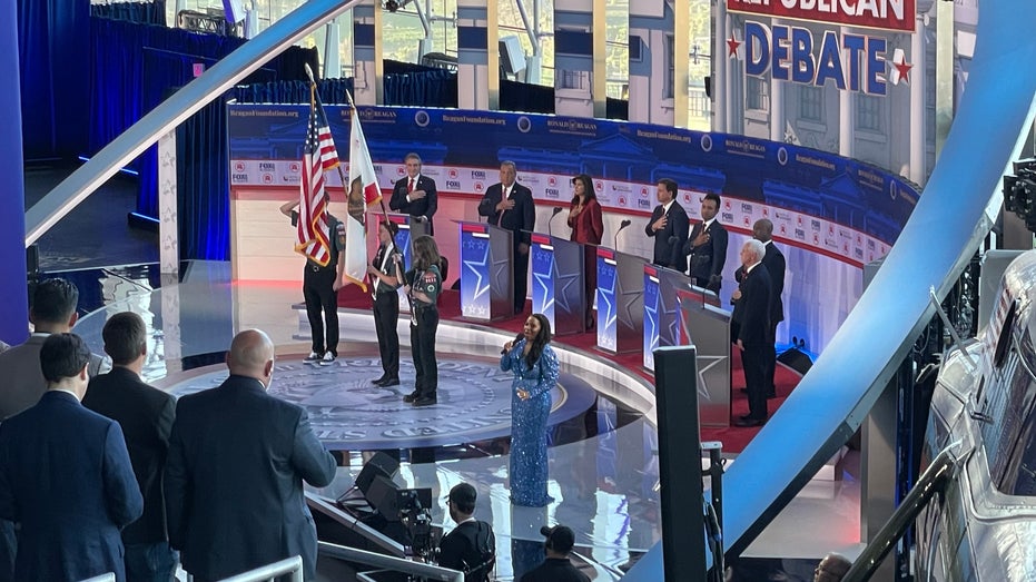 Debate stage with the GOP presidential candidates saluting the American flag
