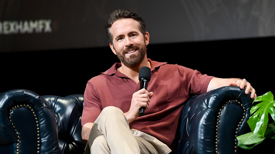 Ryan Reynolds sitting on stage with a microphone