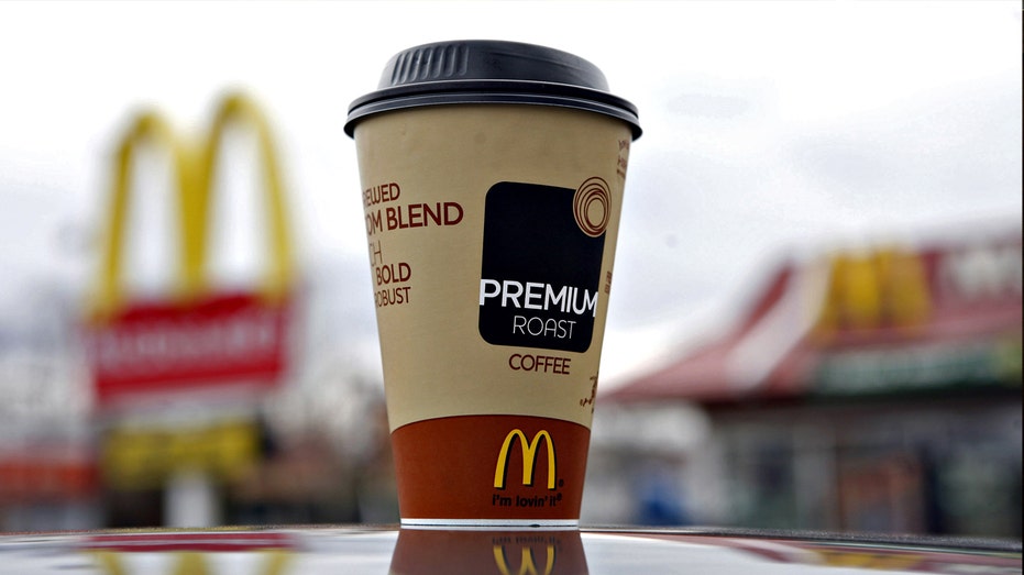 A McDonald's coffee cup sitting on the hood of a car.