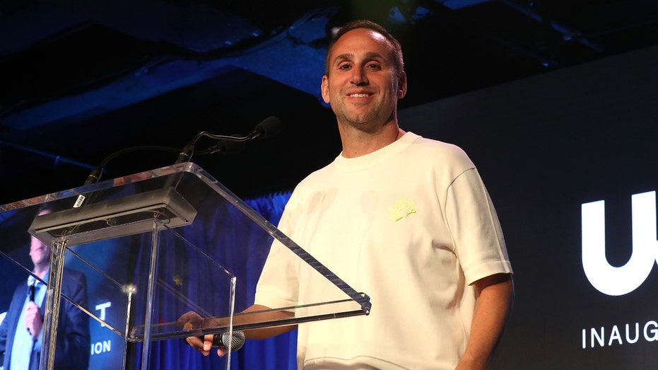 Michael Rubin smiles at podium