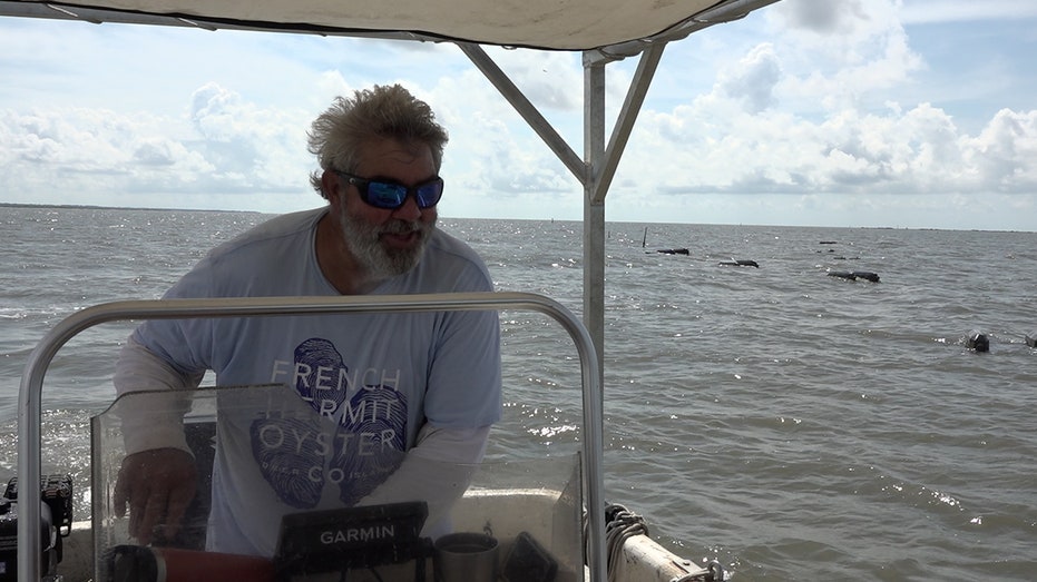 Mike Arguelles steers his boat alongside his oyster cages