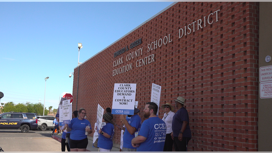 People hold up signs outside an education center