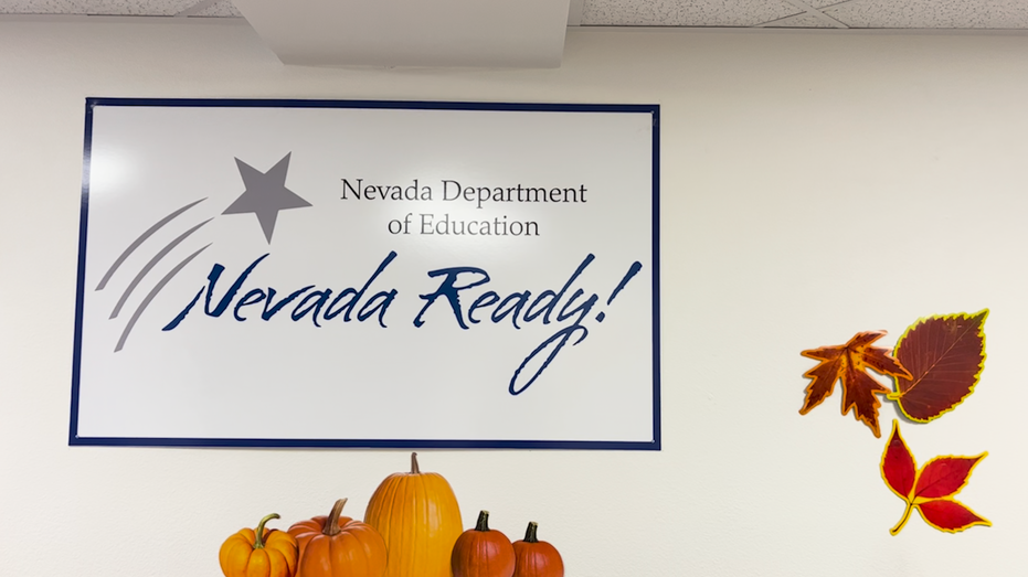 A sign for the Nevada Department of Education hangs on the wall above fall decor.