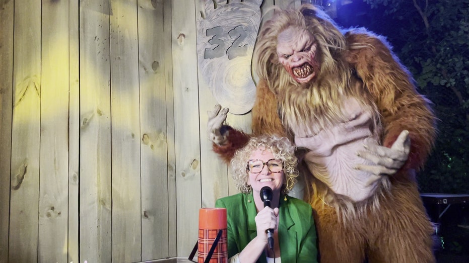 Universal Orlando Assistant Director Lora Sauls at 'YETI: Campground Kills' haunted house at Universal Orlando. A yeti stands behind her.