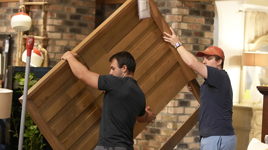 Two men carrying furniture