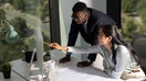 High angle view of a group of architects, young man and his female colleague working together as a team in their office, drawing some schematics and exchanging ideas