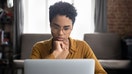 Woman in glasses sit at desk staring at laptop screen, learn new software, makes assignment, working looks concentrated, search solution or ideas. Business challenge, thinks over task concept