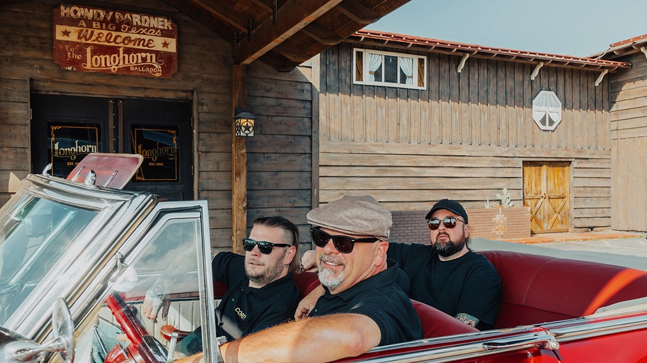 Rick Harrison driving an open top car with his Pawn Stars co-stars