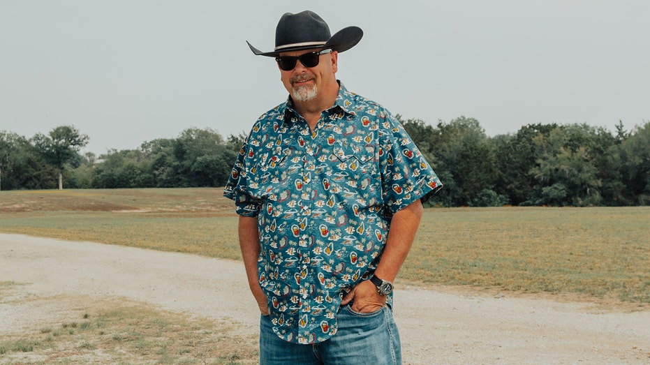 Rick Harrison wearing a printed blue shirt, jeans and a cowboy hat