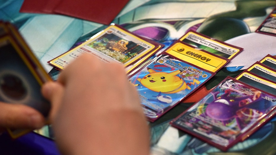 A hand holding a deck of Pokemon cards