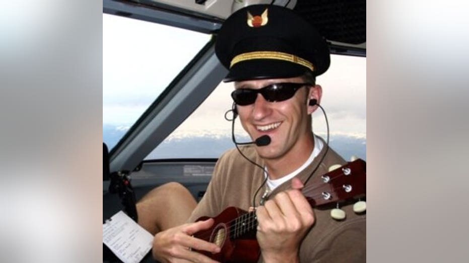 Emerson wears pilot hat and plays ukulele in plane cockpit