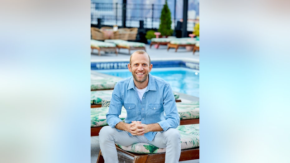 Resort Pass CEO Michael Wolf sits in front of a pool.