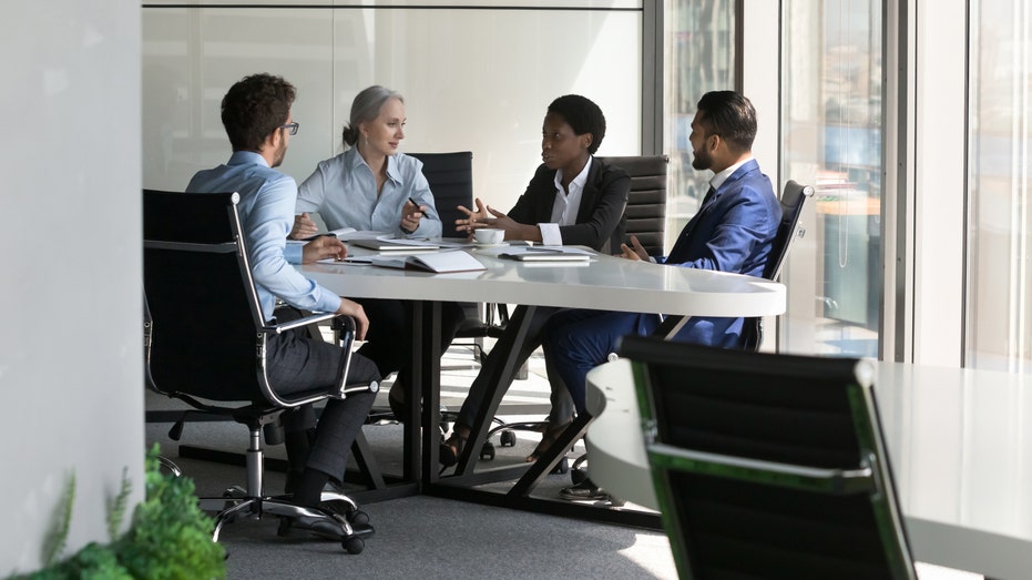 four people sitting at a table in an office