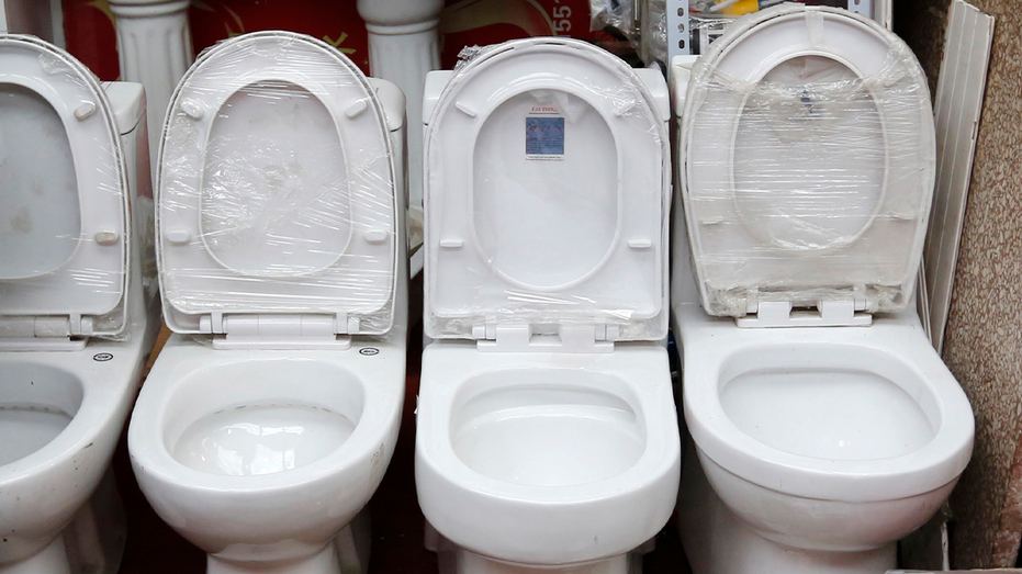 row of toilet bowls with lids up
