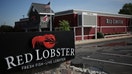 An American flag flies past Red Lobster signage displayed outside of a restaurant location in Clarksville, Indiana, U.S., on Monday, June 22, 2015. Red Lobster is a casual dining restaurant chain that is headquartered in Orlando, Florida. Photographer: Luke Sharrett/Bloomberg via Getty Images
