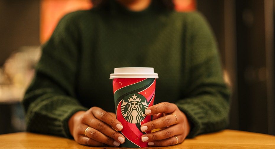 woman holds starbucks holiday cup