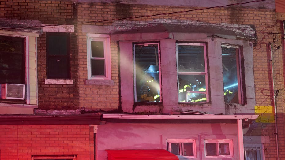 Firefighters search burning second floor room seen through window