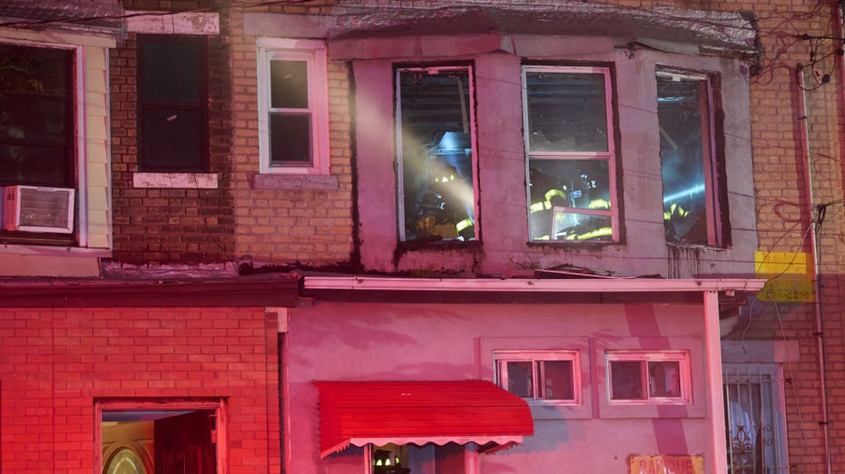 Firefighters search burning second floor room seen through window