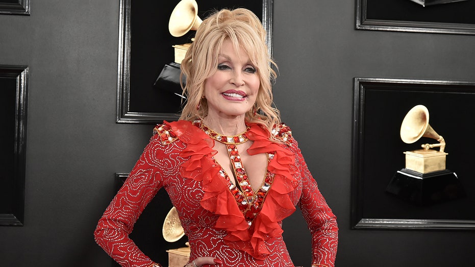 Dolly Parton posing in front of Grammy wall