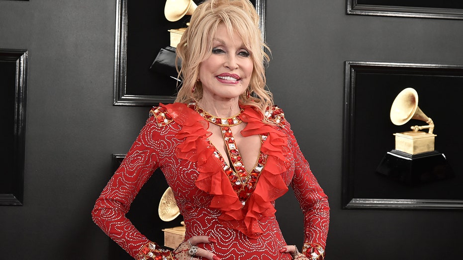 Dolly Parton posing in front of Grammy wall