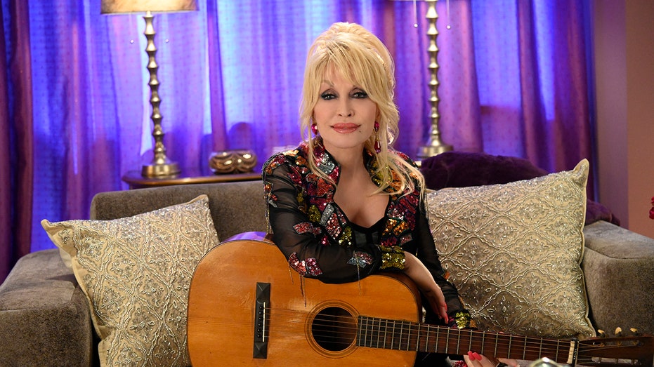 Dolly Parton sitting with a guitar