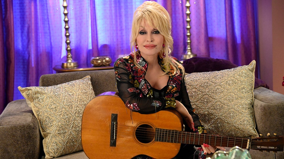 Dolly Parton sitting with a guitar