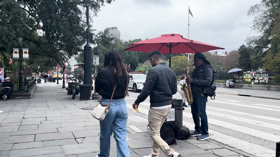 People walking on street next to musician