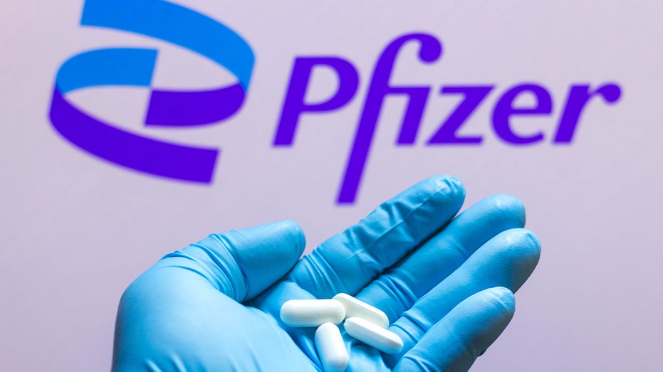 Hand holding pills, Pfizer logo