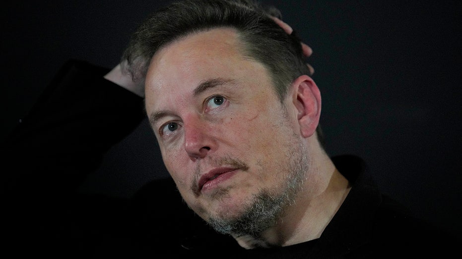 Elon Musk scratches back of his head during AI talks