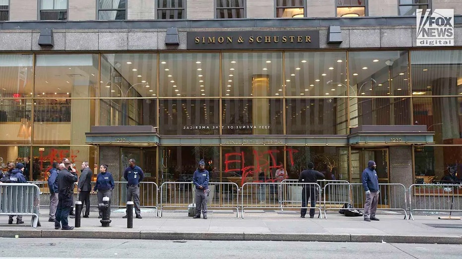 Smashed windows and graffiti are visible on the front windows of Simon & Schuster and Breads Bakery in Midtown Manhattan