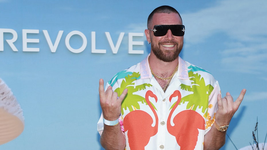 Travis Kelce flashing the rock and roll sign in designer shirt
