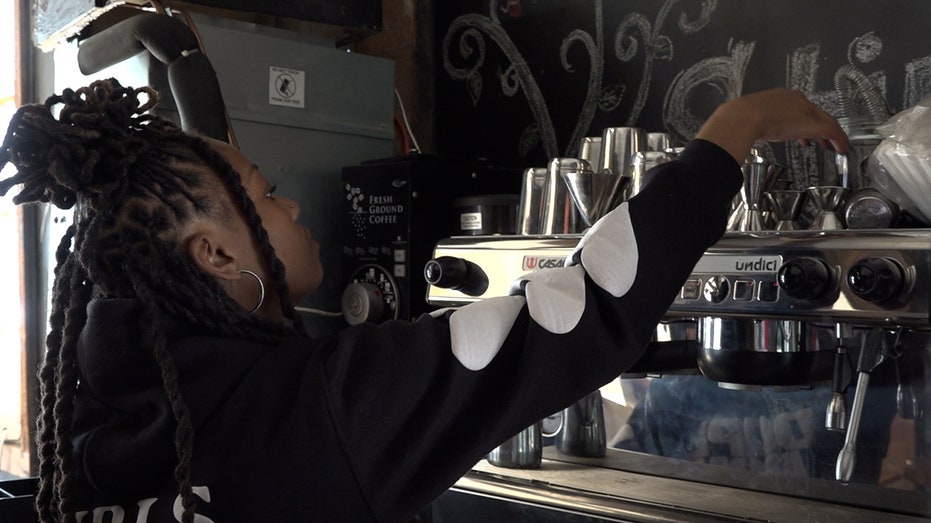Brandi Williams reaches for a cup on top of her coffee machine.