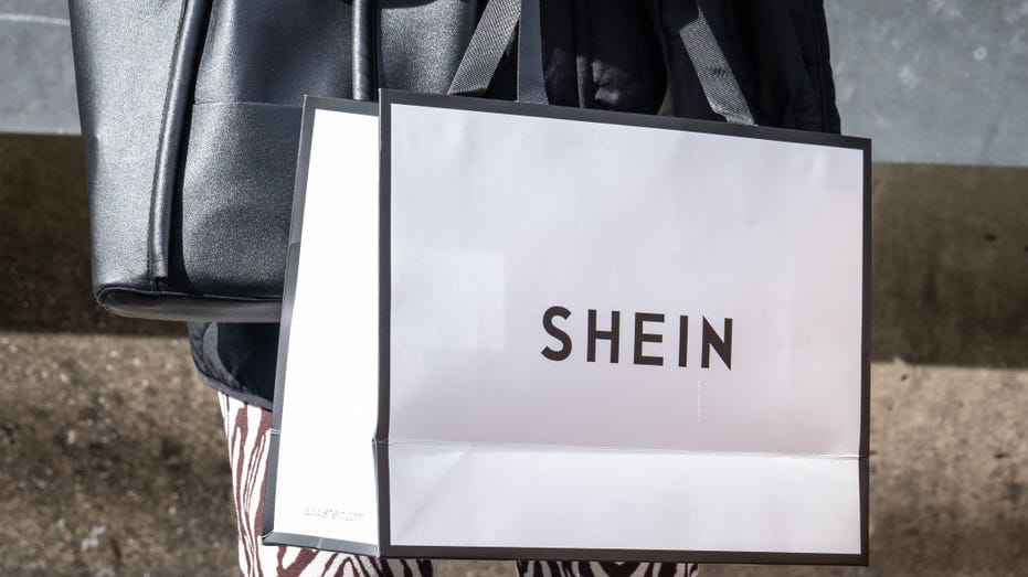 A woman holding a black and white Shein shopping bag.