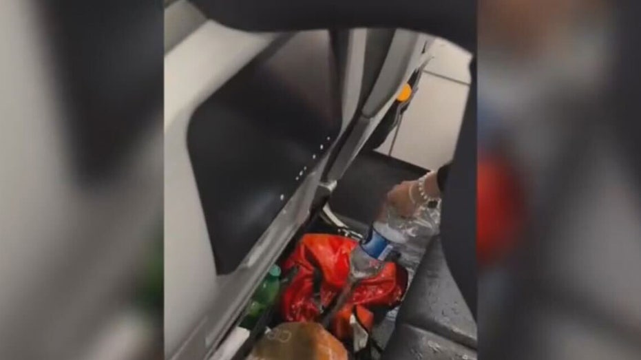 Flight attendant pours water on backpack