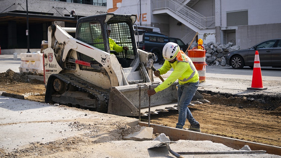 A construction worker hammers a beam