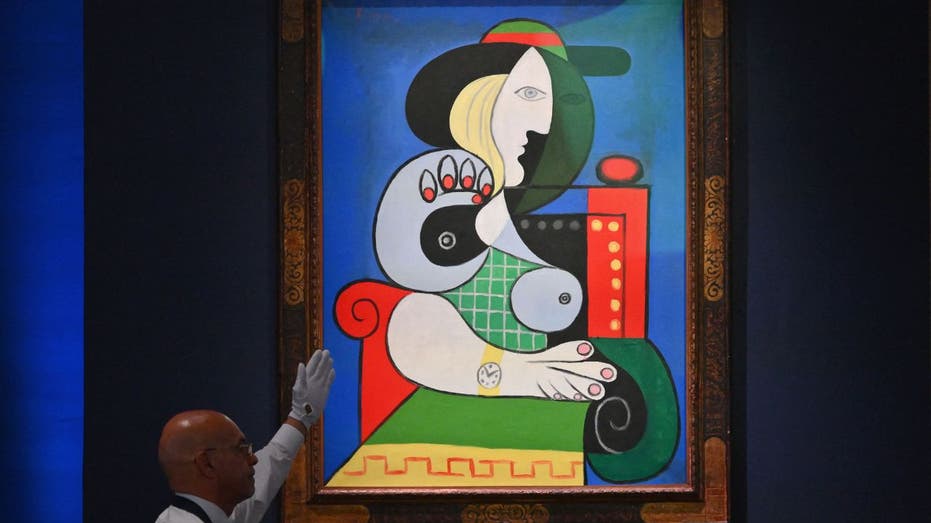 A man holds his hand up to unveil a Picasso paintinng