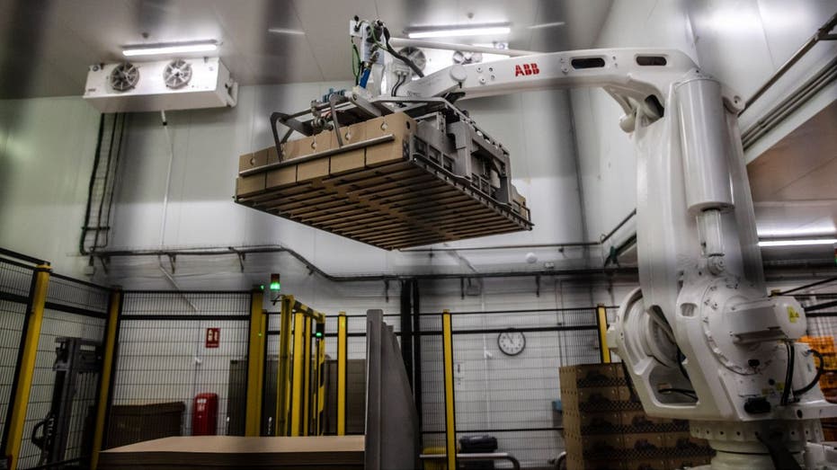 a robotic arm lifts a box in a factory
