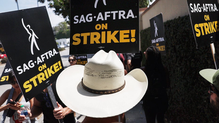 SAG-AFTRA members carry signs while on strike