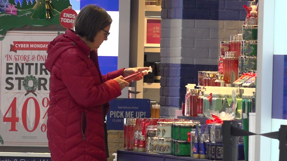 a woman picks up a lotion bottle at bath and body works