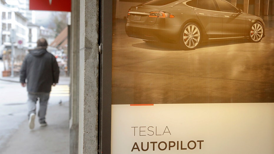 A poster advertises Tesla's autopilot feature